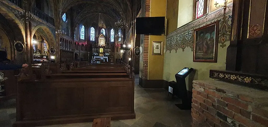 Spendenautomat im Seitenschiff einer gotischen Backsteinkirche neben einer Ziegelbrüstung.